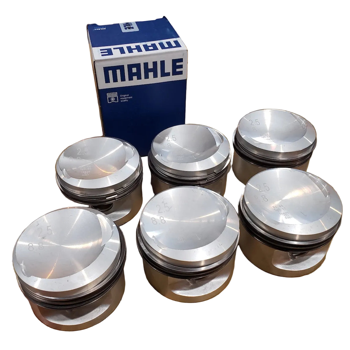 A set of Mahle BMW M20 pistons displayed in front of their packaging box.